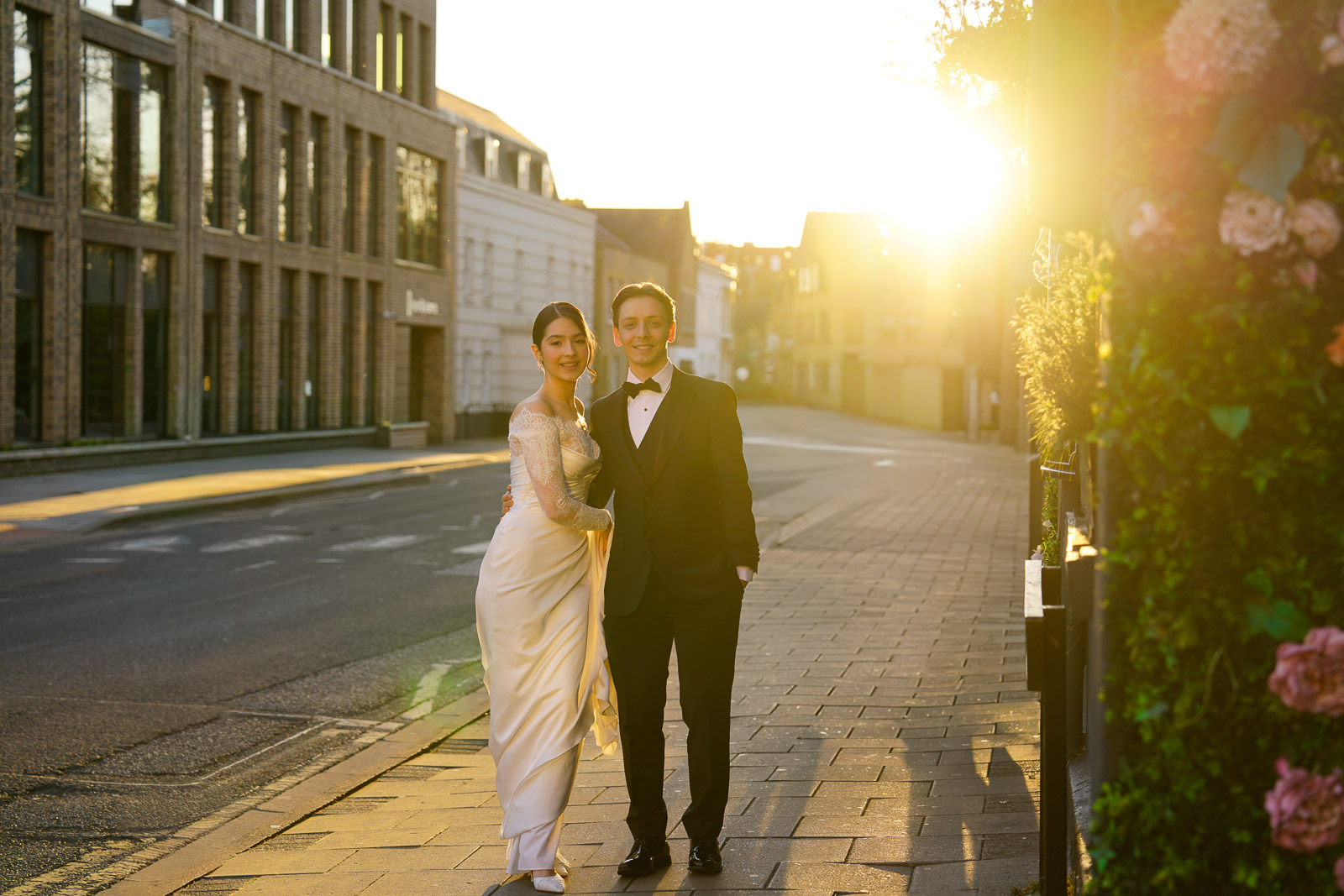 Bride and groom kissing in front of a Gothic castle façade at golden hour