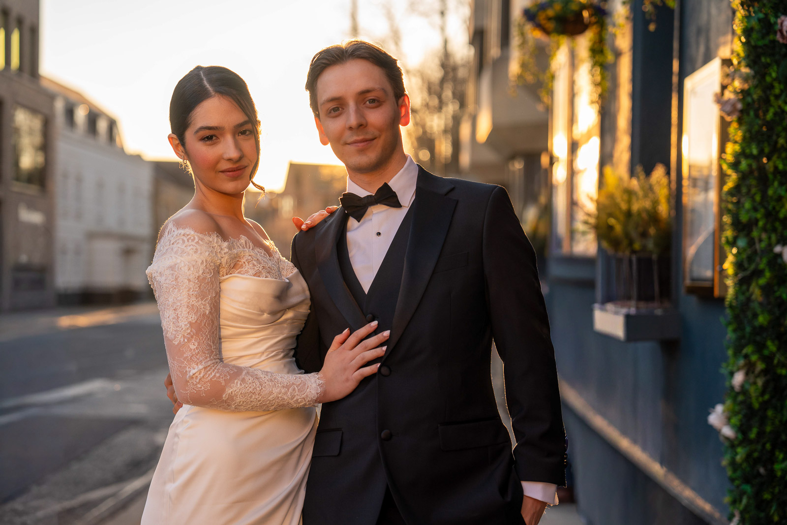 Bride and groom walking in bright backlight, a starburst of sun through trees behind them