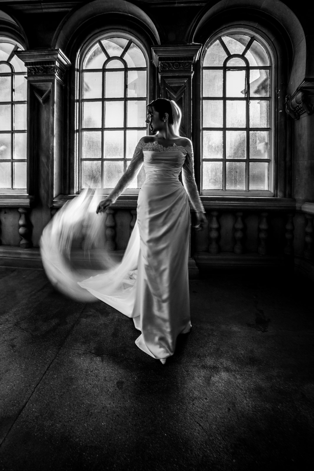 Black and white bridal portrait beside arched windows